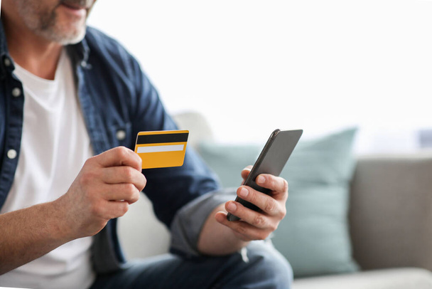 Hombre irreconocible usando smartphone y sosteniendo tarjeta de crédito - Foto, imagen