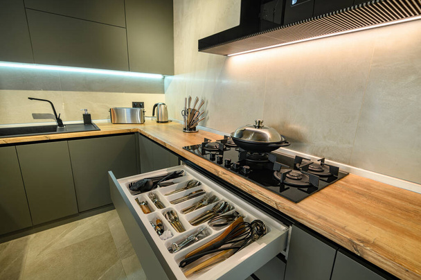 Сучасна велика розкішна темно-сіра кухня з висунутою шухлядою
 - Фото, зображення