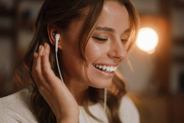 Close up of a pretty smiling woman in earphones at the office - Фото, изображение
