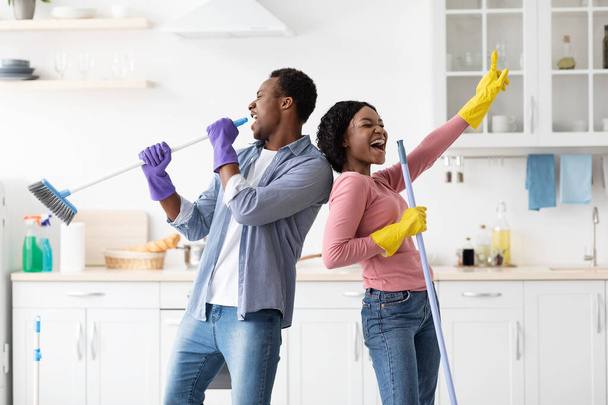 Αστείο μαύρο ζευγάρι τραγουδά ενώ καθαρίζει την κουζίνα - Φωτογραφία, εικόνα