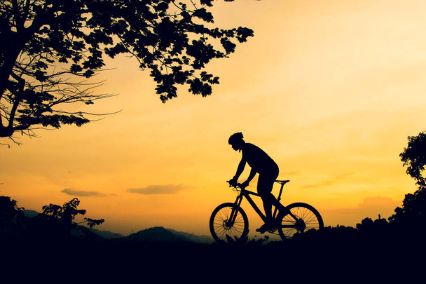 Μια σιλουέτα ενός βουνού ποδηλασία εξάσκηση ποδήλατα σε ένα ψηλό βουνό - Φωτογραφία, εικόνα