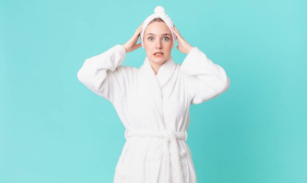 blond pretty woman feeling stressed, anxious or scared, with hands on head and wearing bathrobe - Foto, Bild