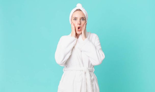 blond pretty woman feeling shocked and scared and wearing bathrobe - Φωτογραφία, εικόνα
