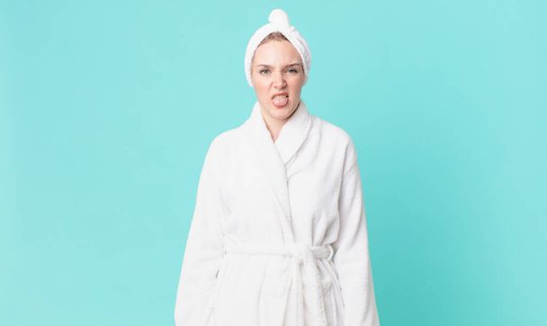 blond pretty woman feeling disgusted and irritated and tongue out and wearing bathrobe - Foto, Imagem