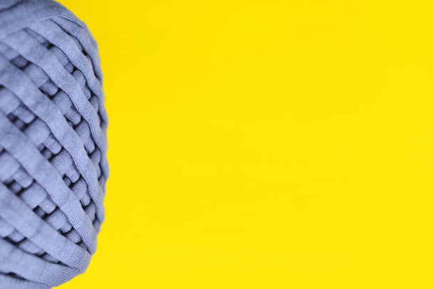 Primer plano de hilo gris (prendas de punto) sobre un fondo amarillo-un diseño diseñado para crocheting.The concepto de su hobby favorito es tejer artículos interiores.Los colores de 2021.Vista superior.Flatly.Copyspace. - Foto, Imagen