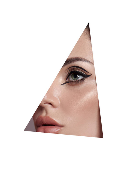 Beauty makeup women, eye brows eyelashes and lips in a triangular hole paper white background. Professional beauty makeup, place for text, copy space - Фото, изображение