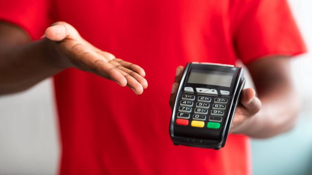 Nahaufnahme eines schwarzen Mannes, der einen Kassenautomaten zur Bezahlung hält - Foto, Bild