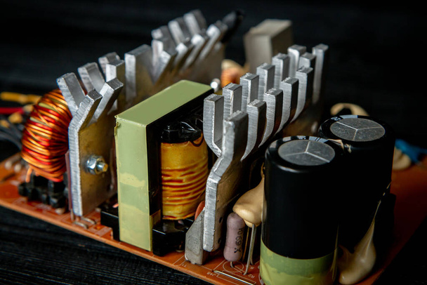 Onderdeel van pc-voeding met radiator en elektronisch bord met geïntegreerde stabilisatoren en filtercondensator met spoelen - Foto, afbeelding