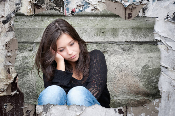 Σκισμένη φωτογραφία μιας θλιμμένης έφηβης που σκέφτεται προβλήματα καρφωμένα σε έναν παλιό ξύλινο τοίχο με υπολείμματα χαρτιού - Φωτογραφία, εικόνα