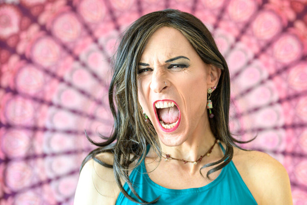 Portrét plačícího transsexuála s ústy a očima dokořán otevřenýma před barevným pozadím - Fotografie, Obrázek