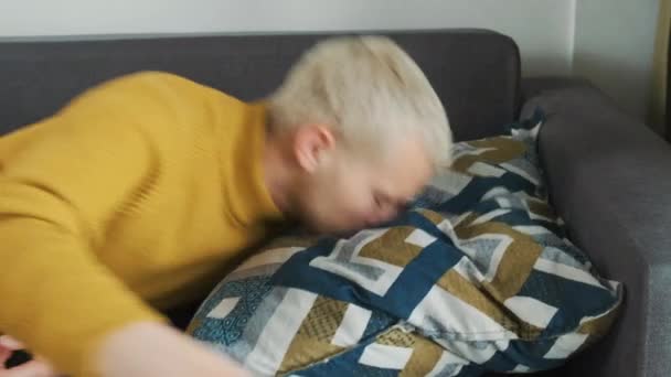 Jeune Européen épuisé ou ennuyé mâle tombe littéralement sur le canapé oreiller après une dure journée de travail et s'endort. - Séquence, vidéo