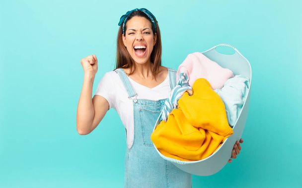 young hispanic woman shouting aggressively with an angry expression and washing clothes - Фото, зображення