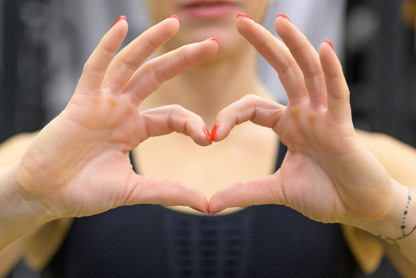 Жінка робить романтичний знак серця з пальцями символ любові в крупним планом на її руках
 - Фото, зображення