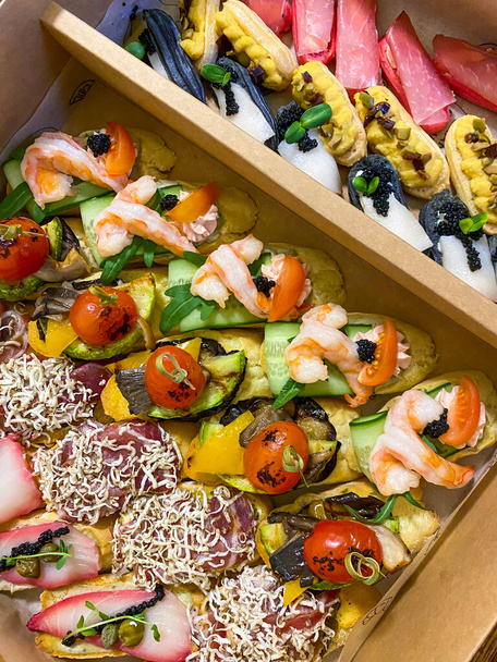 Boîte de petits sandwichs avec charcuterie, légumes grillés, fromage et fruits de mer. Charcuterie planches à commander - Photo, image