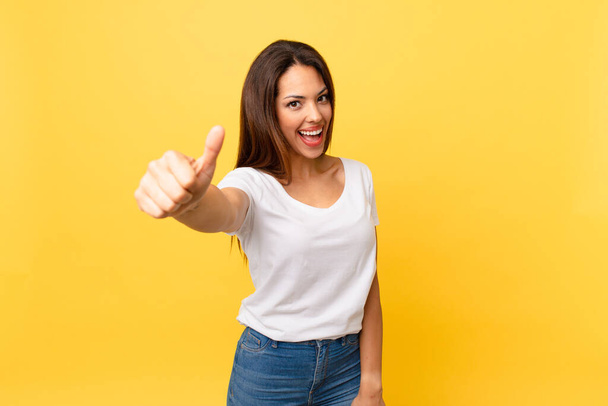 young hispanic woman feeling proud,smiling positively with thumbs up - Photo, Image