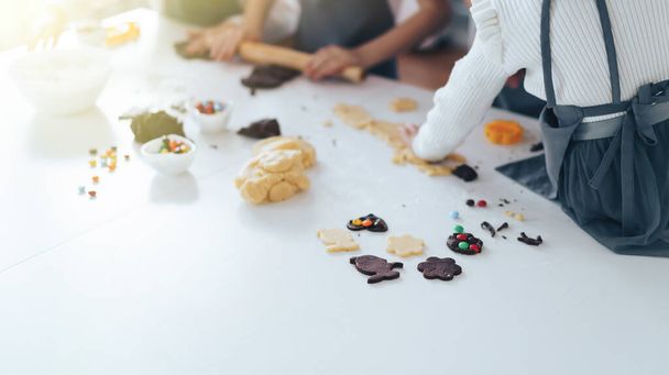 Kinder bereiten Plätzchen mit Süßigkeiten zu, ein Junge rollt den Teig mit dem Nudelholz aus. Freizeitaktivitäten mit Kindern. - Foto, Bild