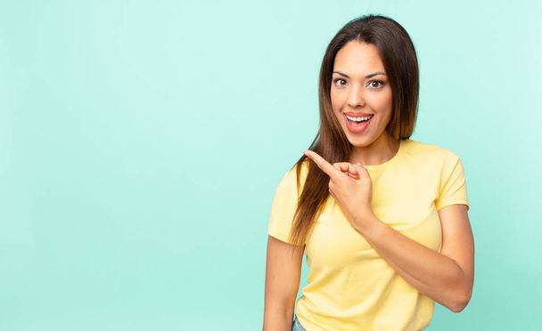 young hispanic woman looking excited and surprised pointing to the side - Фото, зображення
