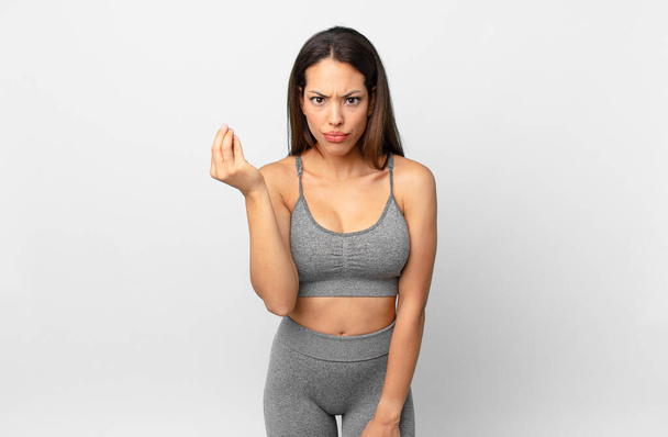young hispanic woman making capice or money gesture, telling you to pay. fitness concept - Photo, image