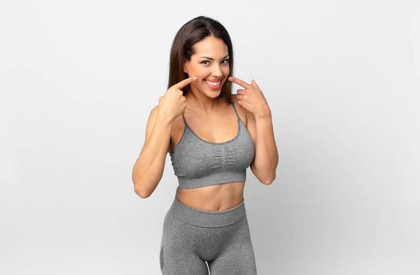 young hispanic woman smiling confidently pointing to own broad smile. fitness concept - Фото, изображение