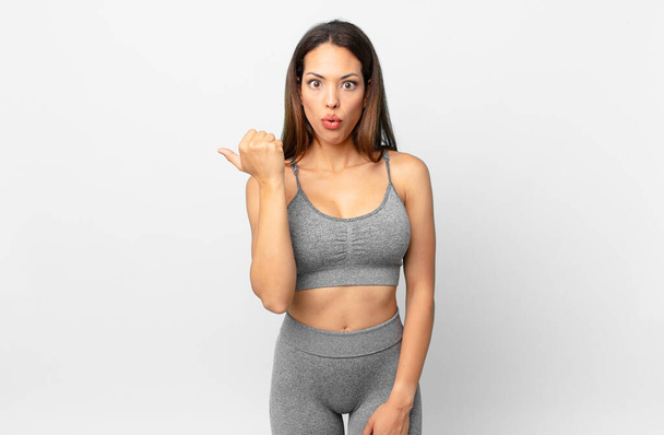 young hispanic woman looking astonished in disbelief. fitness concept - 写真・画像