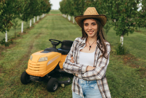 woman posing in front of lawn mower - Φωτογραφία, εικόνα
