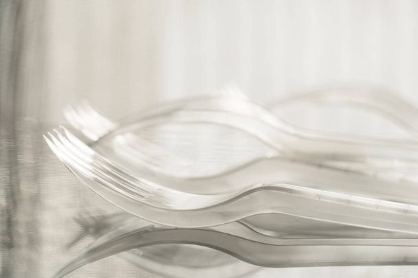 Natura morta di forchette monouso in plastica trasparente bianca per asportare cibo con luce solare morbida - Foto, immagini