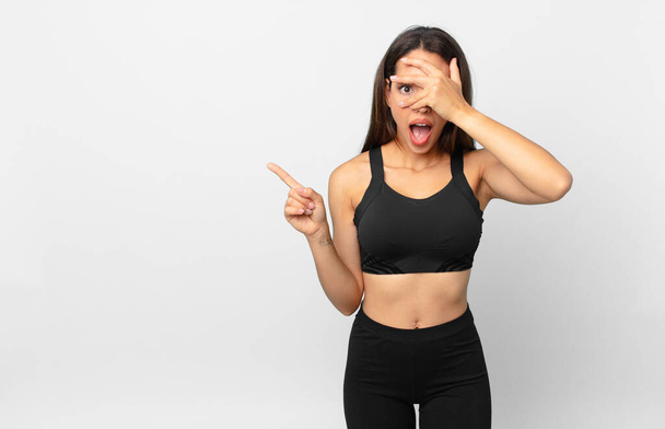 young hispanic woman looking shocked, scared or terrified, covering face with hand. fitness concept - Zdjęcie, obraz