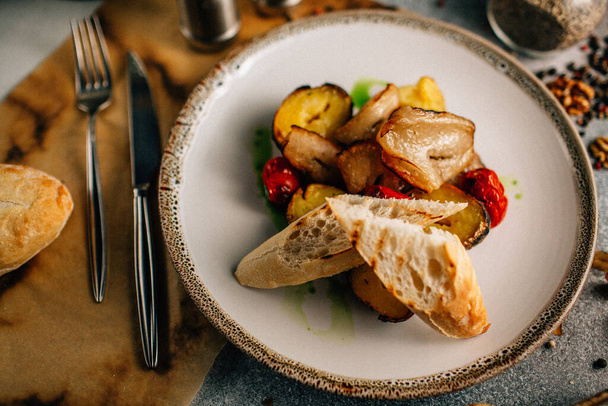 gegrild vlees met aardappelen en groenten met brood op wit bord, van dichtbij bekeken  - Foto, afbeelding