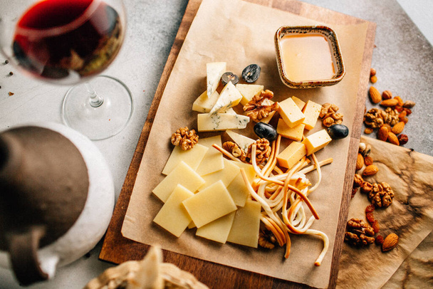 テーブルの上に蜂蜜とブドウとナッツとチーズプレートと木製の板,近いビュー  - 写真・画像