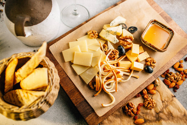 wooden board with cheese platter with grape and nuts with honey on table, close view  - Fotografie, Obrázek