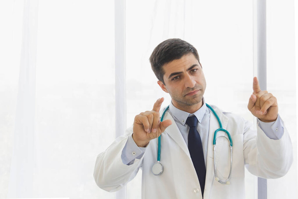 male doctor raised two finger for posture with white room background at hospital - Photo, Image