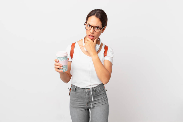 young hispanic woman with mouth and eyes wide open and hand on chin. student concept - Photo, Image