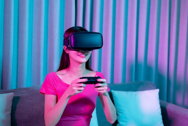 asian woman wears vr glasses with gamepad and play video games happily at home - Foto, afbeelding