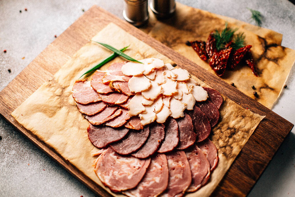 wooden board with cold cuts on table, close view  - Фото, изображение