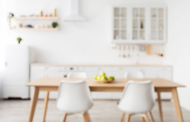 Rozmazané pozadí lehkého kuchyňského interiéru ve skandinávském stylu s dřevěným jídelním stolem, kopírovací prostor - Fotografie, Obrázek