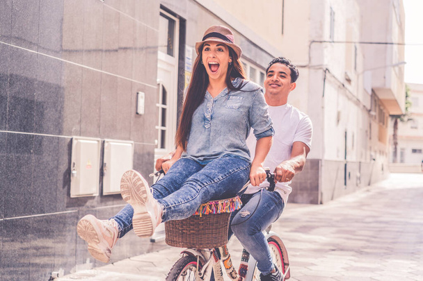 İnsanlar, eğlence ve yaşam tarzı konsepti. Şehirde bisiklet süren mutlu genç çift. - Fotoğraf, Görsel