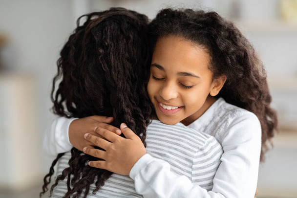 adorabile ricci nero scuola ragazza abbracciare il suo mamma - Foto, immagini
