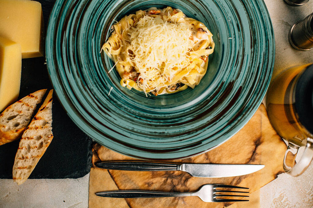 pasta con queso en el plato cerca de la tetera en la mesa - Foto, Imagen