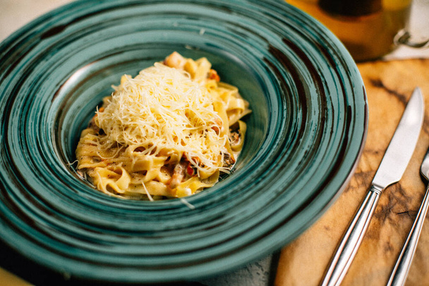 těstoviny se sýrem na talíři u konvice na stole - Fotografie, Obrázek