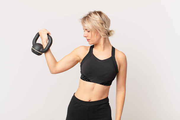blond pretty woman lifting a dumbbell - Photo, image