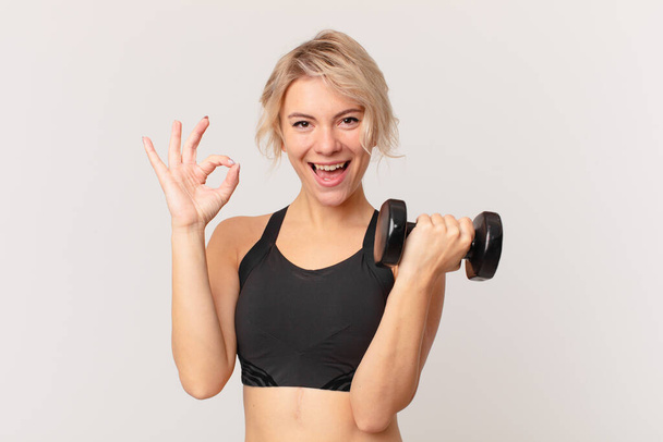 blond pretty woman lifting a dumbbell - Photo, Image