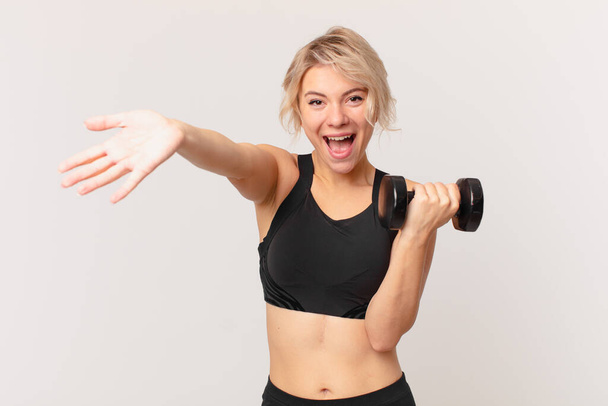 blond pretty woman lifting a dumbbell - Photo, Image