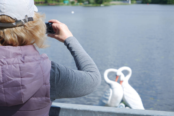 Una chica con una gorra blanca toma fotos del paisaje acuático con una cámara. Día de San Veronicas Día de los Fotógrafos . - Foto, Imagen