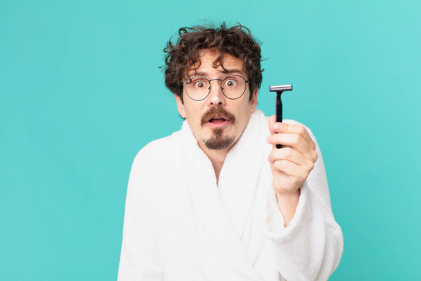 young crazy man shaving his beard with a razor - 写真・画像