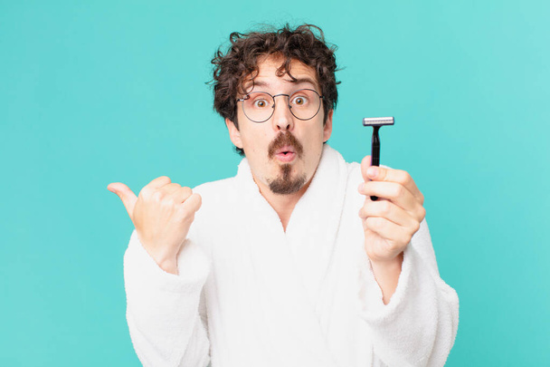 young crazy man shaving his beard with a razor - Фото, изображение