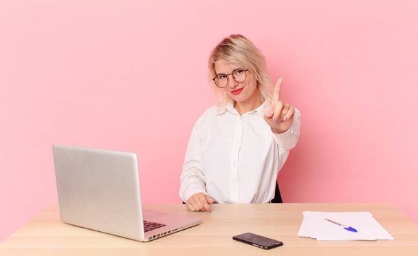 blonde pretty woman young pretty woman smiling proudly and confidently making number one. workspace desk concept - Foto, Imagen