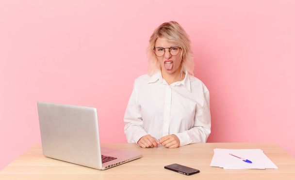 blonde pretty woman young pretty woman feeling disgusted and irritated and tongue out. workspace desk concept - 写真・画像