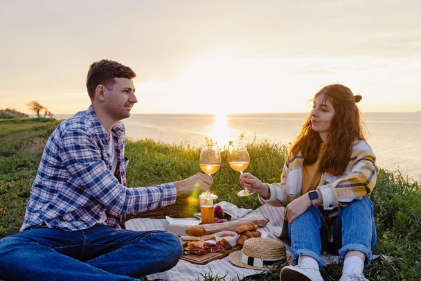 Couple having picnic on green lawn with a sea view - Photo, image
