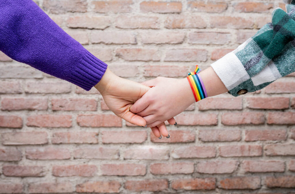 manos de dos mujeres con arcoíris brazalete gay orgullo - Foto, Imagen
