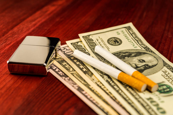 Two cigarettes and lighter are on the dollars. Focus on the ligh - Foto, Imagem